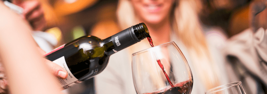 Kobieta promująca restaurację poprzez nalewanie czerwonego wina do kieliszka w marketingu w mediach społecznościowych.